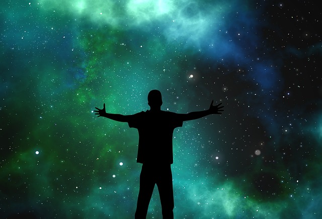 Cień człowieka stojącego z rozłożonymi na boki rękami na tle rozgwieżdżonego nocnego nieba w odcieniach zieleni